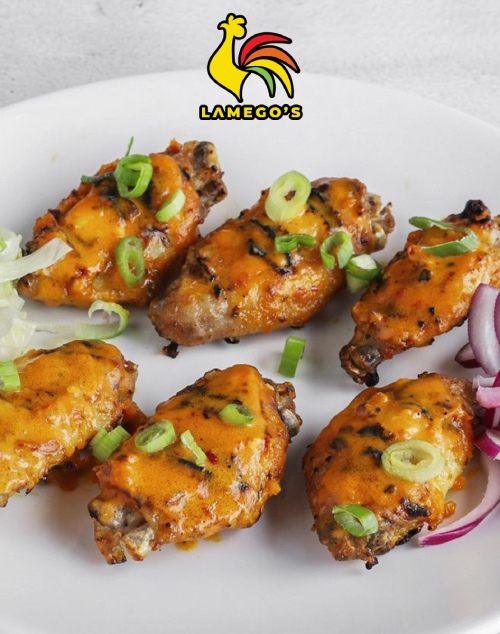 Lamego’s grilled cheesy chicken wings with spring onions served on a plate with veggies.